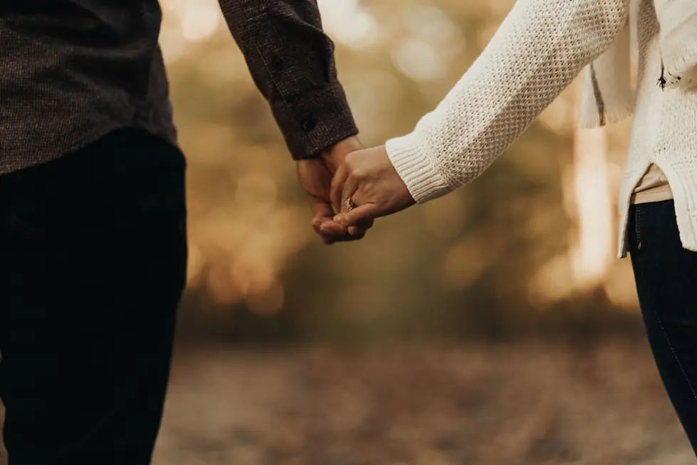 Two people holding hands in soft light, faces out of frame
